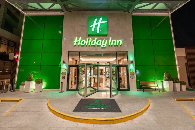 Entrance of the Holiday Inn Ankara – Çukurambar at night, with the green Holiday Inn sign above the revolving door